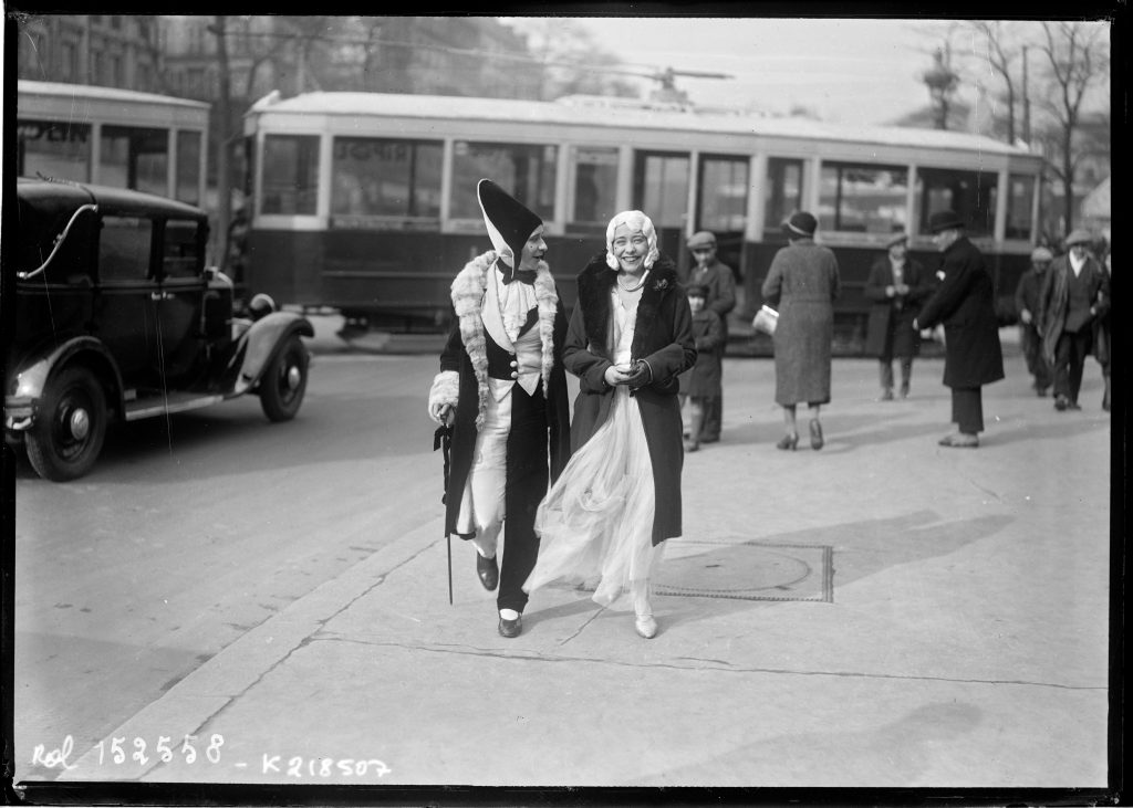 Deux femmes costumées traversant une rue devant un tramway et des passants