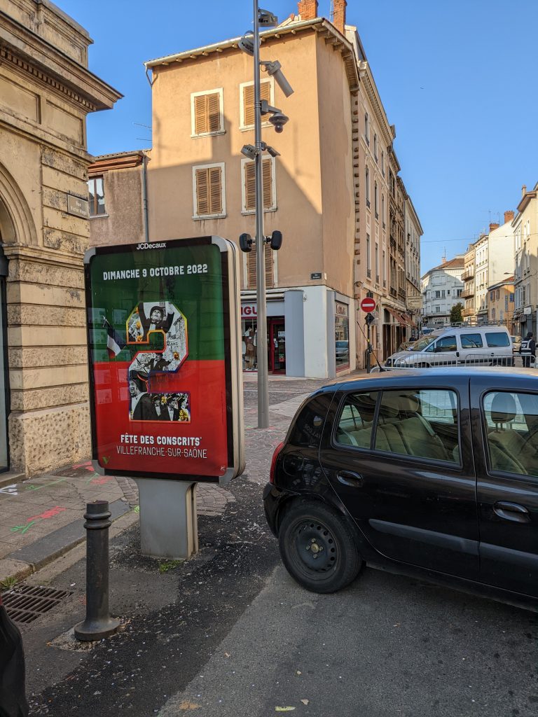 Panneau publicitaire annonçant la Fête des Conscrits de Villefranche-sur-Saône dans une rue