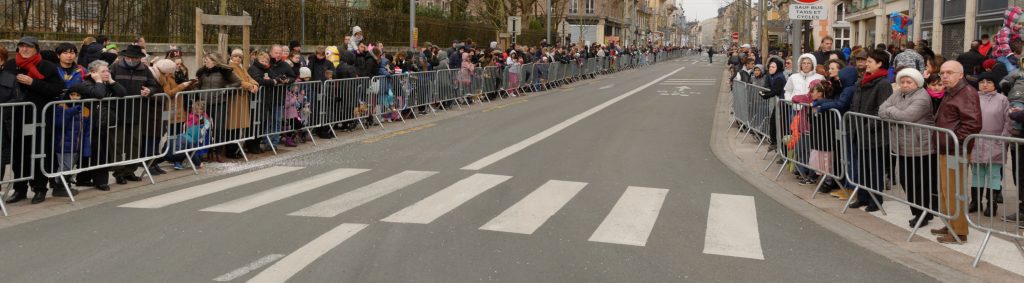 Foule en manteaux d'hiver derrière des barrières le long d'une avenue vide