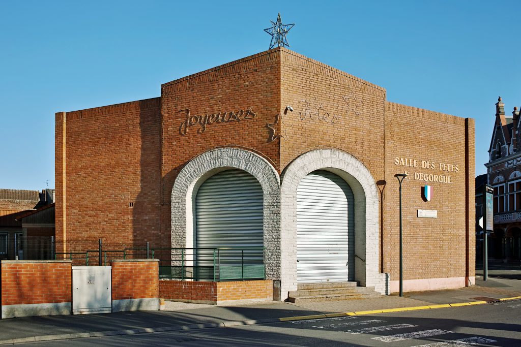 Façade en brique d'une salle des fêtes, décor lumineux « Joyeuses Fêtes » et étoile