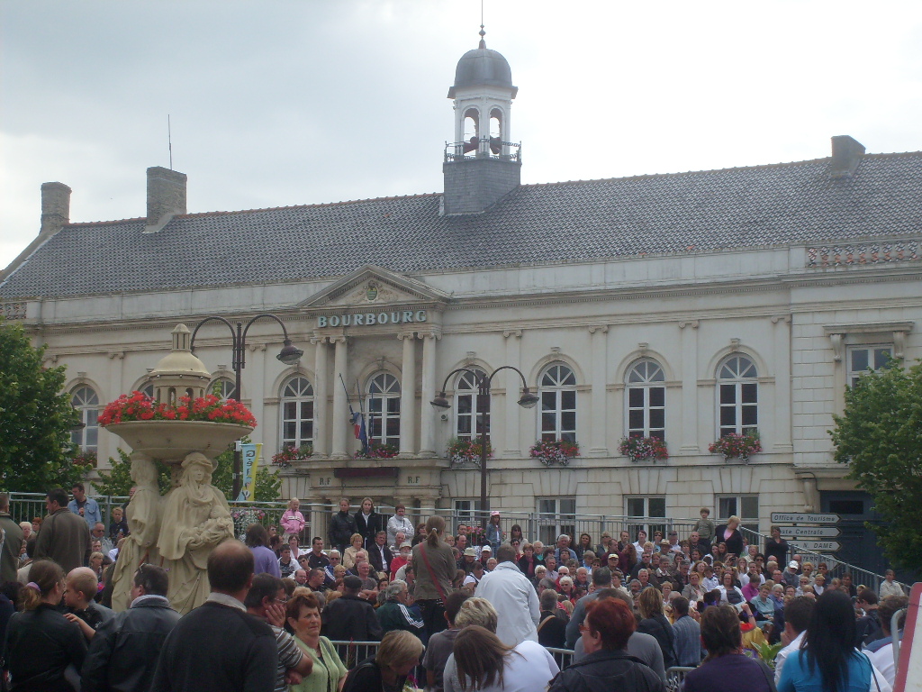 Foule rassemblée devant la mairie de Bourbourg et sa fontaine fleurie un jour de fête