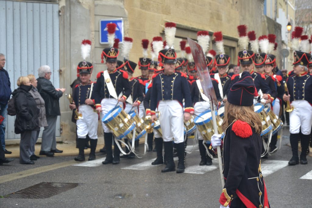 Défilé de tambours et clairons en uniformes napoléoniens dans une rue, spectateurs au bord