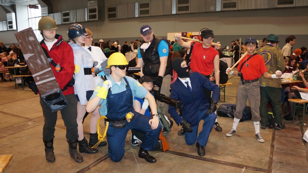 Groupe de cosplayeurs costumés posant dans un hall de convention bondé