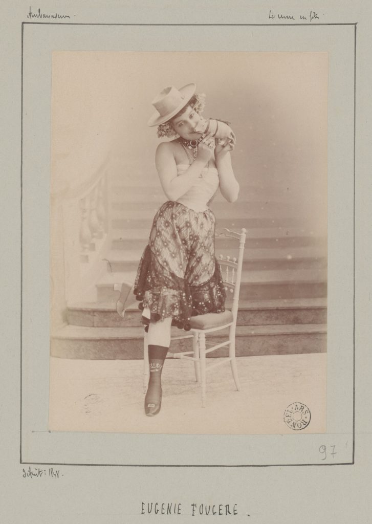 Portrait ancien d'une chanteuse en costume de scène, chapeau et jupe brodée, près d'une chaise
