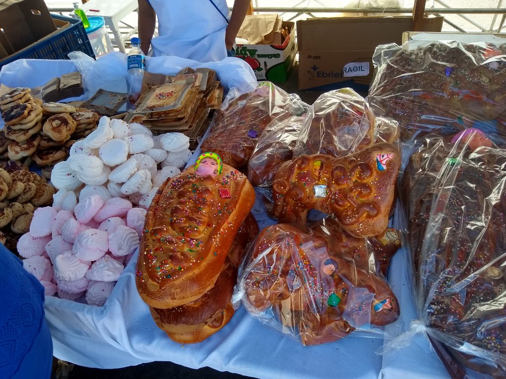 Étal de marché garni de pains décorés, meringues roses et blanches et biscuits