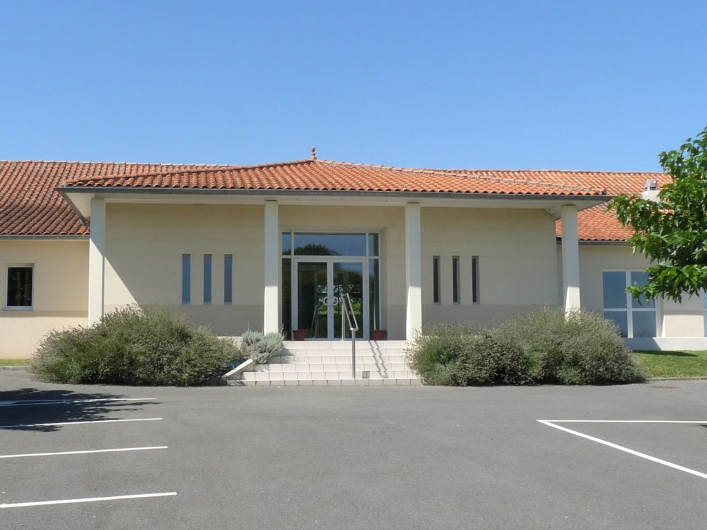 Salle des fêtes moderne à toit de tuiles, entrée vitrée, lavandes et parking goudronné