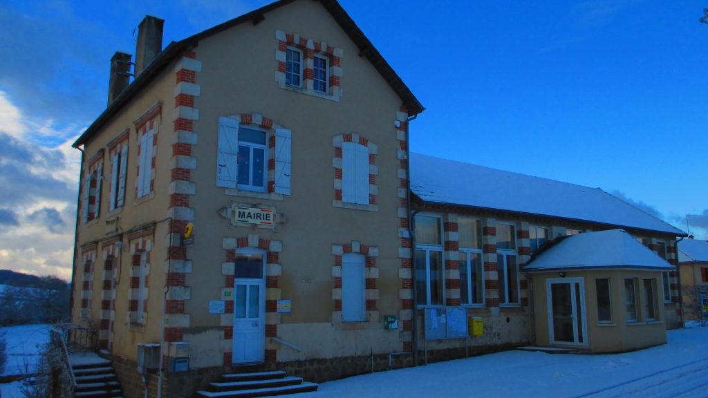 Mairie de village en pierre et brique sous la neige au crépuscule