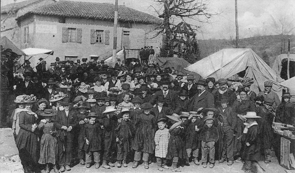 Foule d'habitants et d'enfants posant devant des tentes de foire, village ancien