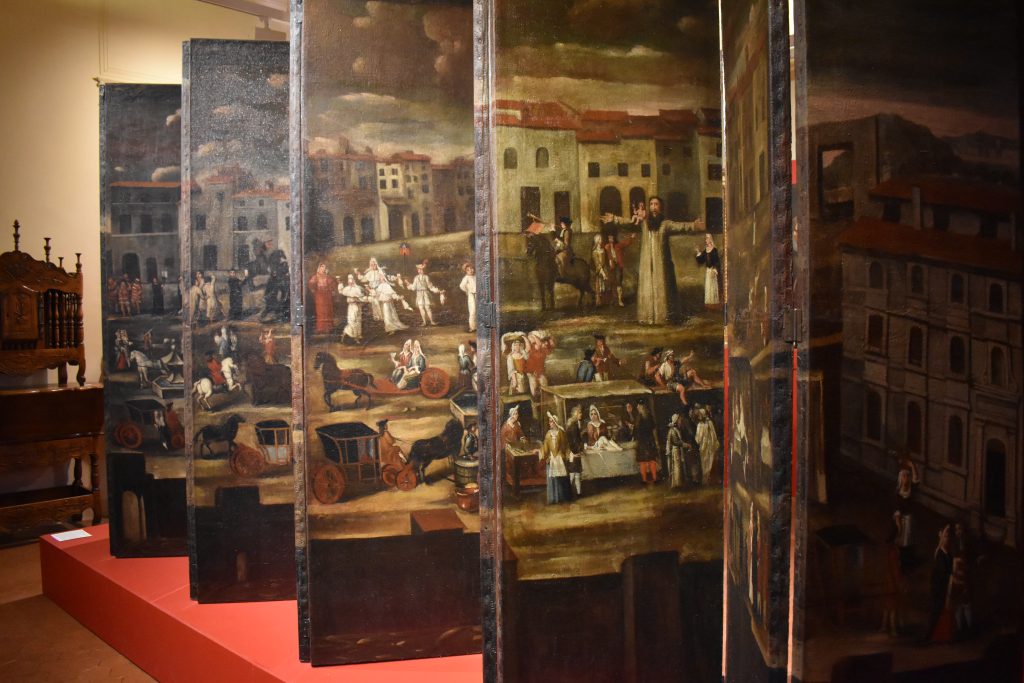 Paravent peint ancien exposé en musée, scènes de fête de village sur place animée