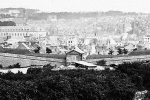Vue ancienne en noir et blanc d'une ville depuis des remparts, toits et clocher